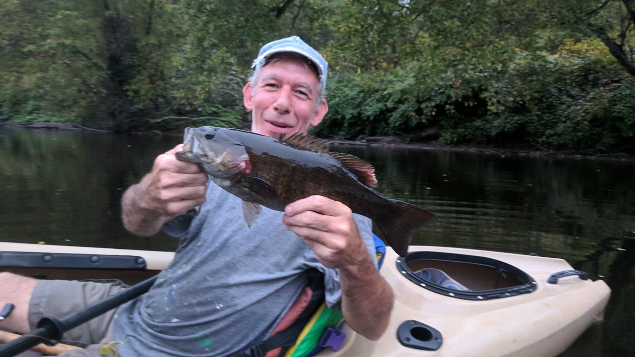 An angler holding a smallmouth bass caught on the North Branch of the Potomac.