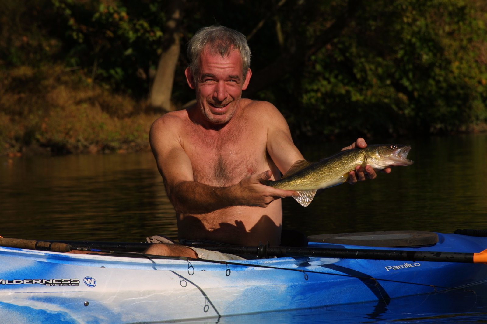 A fish breaking the water's surface beside a kayak, mid-catch.