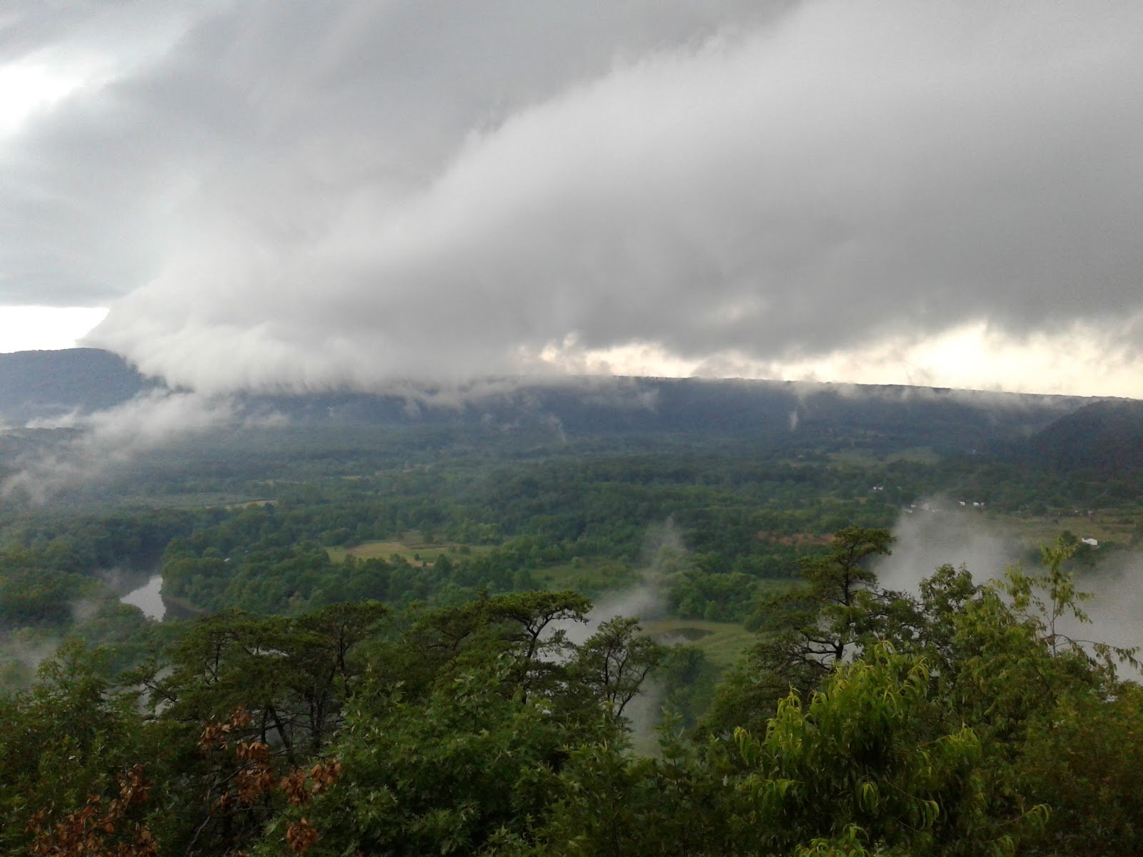 Storm clouds rolling over the mountain and river valley.