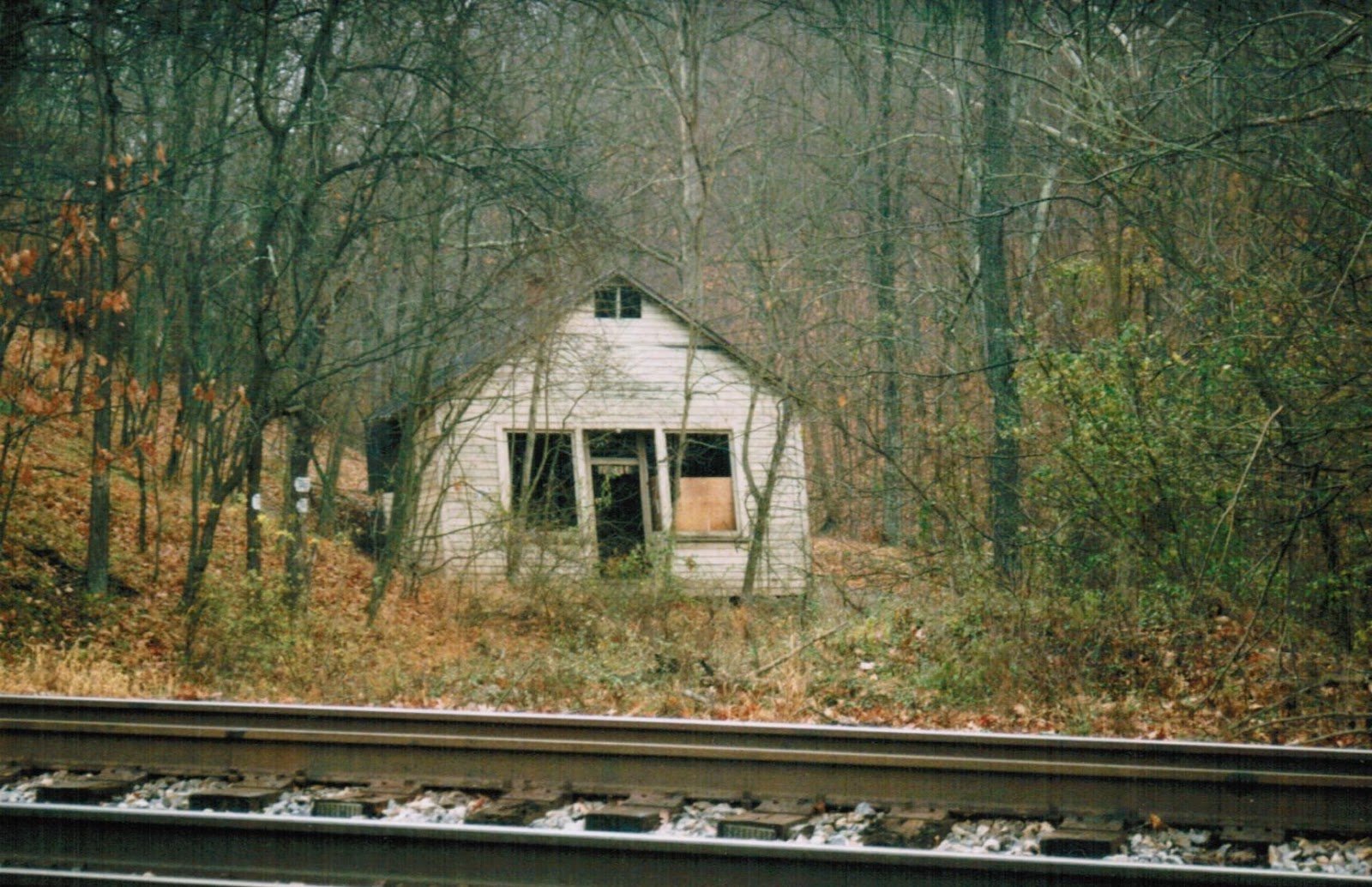 Abandoned store and post office building in the woods beside the tracks, before it was dismantled.