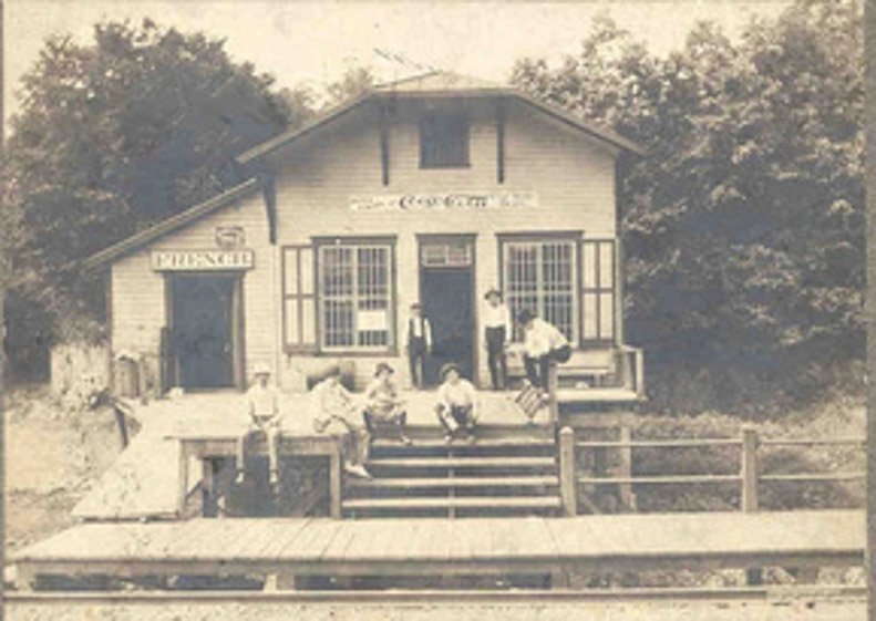 A group photo outside the French store, with a Coca-Cola advertisement on the gable.